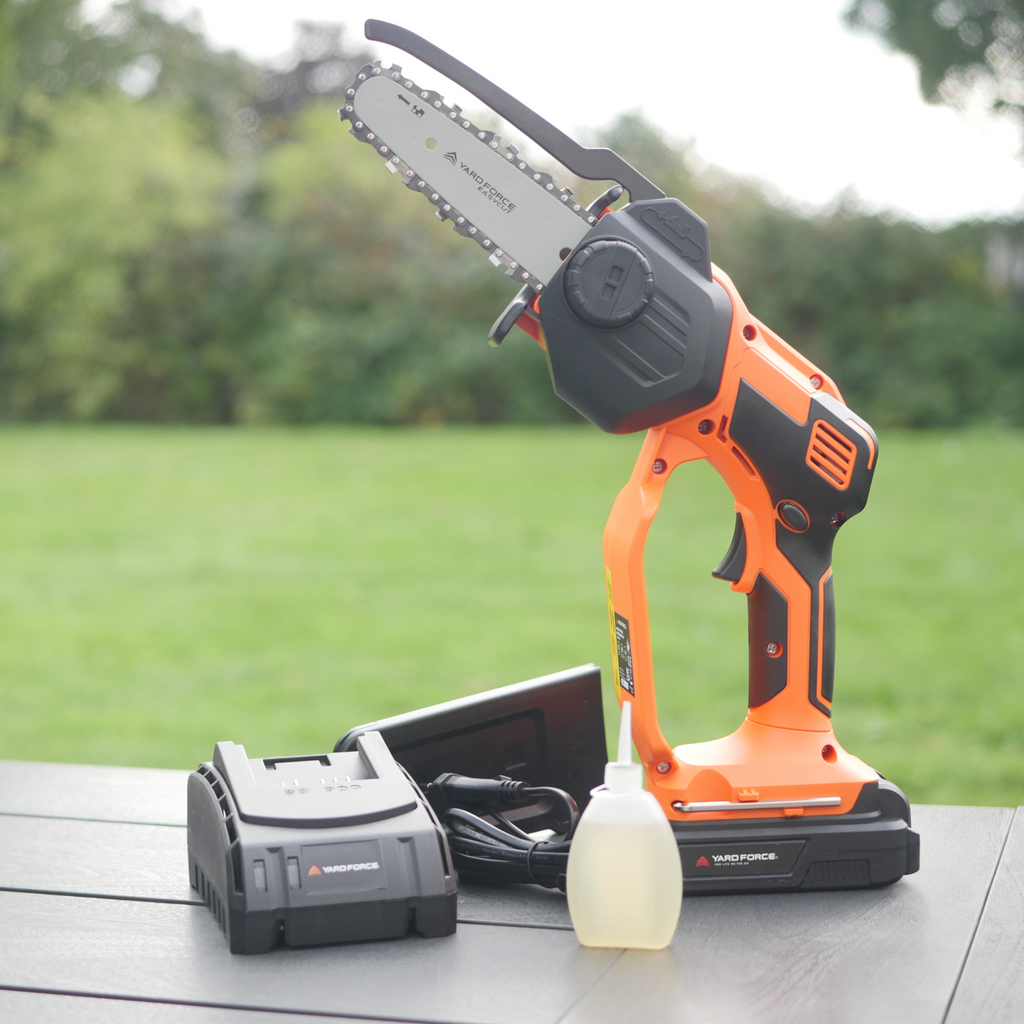 Mini-tronçonneuse Yard Force LS C13A : outil, chargeur et huile sur une table de jardin.