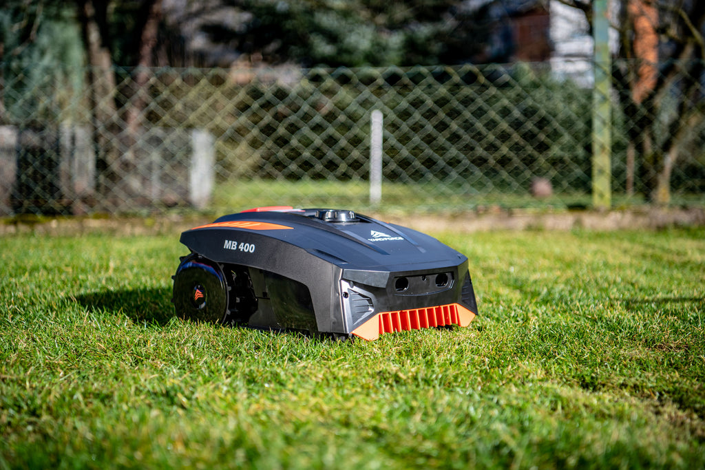 Robot tondeuse Yard Force MB400 : robot sur la pelouse près d'une clôture.