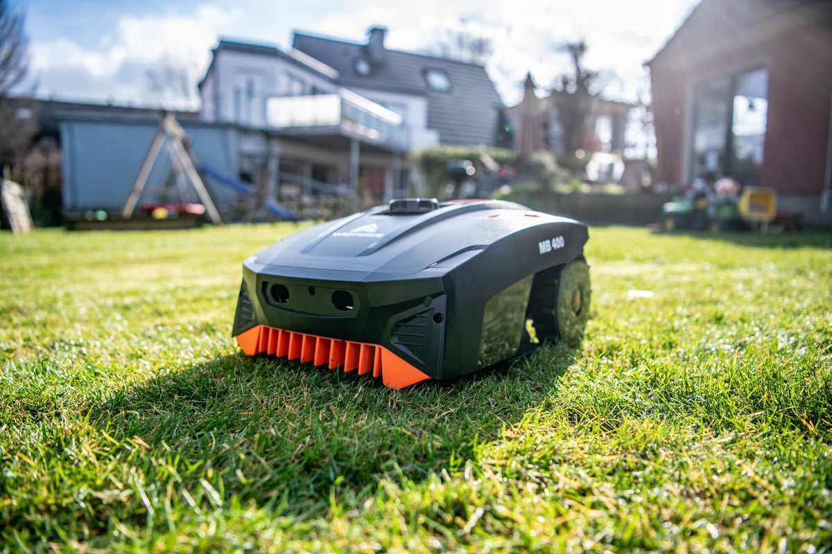 Robot tondeuse Yard Force MB400 : robot sur une pelouse devant une maison.
